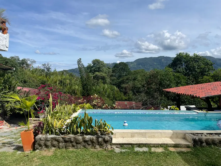 La piscina de la casona, con el jardín alrededor y las montañas de Calambeo detrás